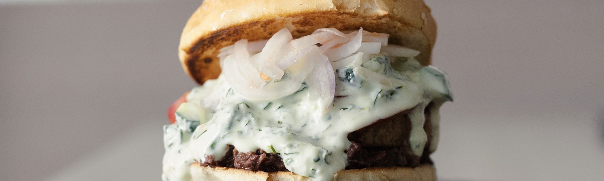 Hamburger vegetale con cipolla rossa, salsa tzatziki, olive e pomodoro – ingredienti e preparazione